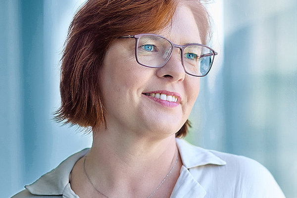 Bild einer Ärztin mittleren Alters mit halblangen rot-braunen Haaren und Brille, die freundlich lächelt