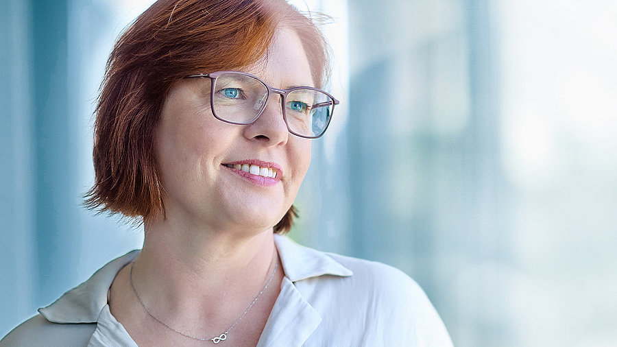 Bild einer Ärztin mittleren Alters mit halblangen rot-braunen Haaren und Brille, die freundlich lächelt