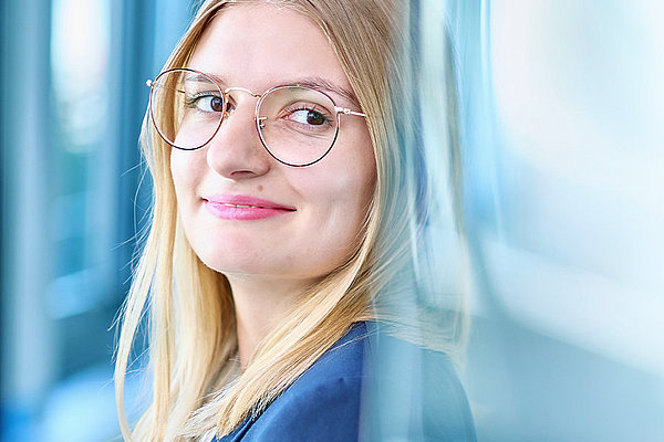 Bild: junge Frau mit Brille und glatten, blonden Haaren, die freundlich lächelt