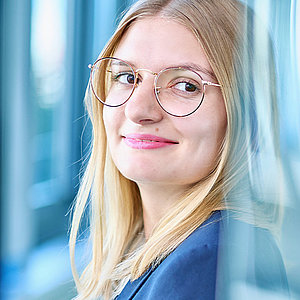 Bild: junge Frau mit Brille und glatten, blonden Haaren, die freundlich lächelt