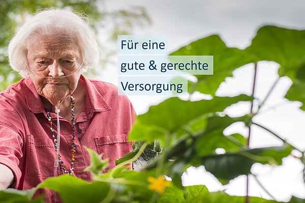 Foto einer grauhaarigen, betagten Frau, die einen Schlauch zur Beatmung bis zu ihrer Nase trägt. Sie steht hinter grünen Blättern und macht scheinbar Gartenarbeit. Auf dem Foto steht "Für eine gute und gerechte Versorgung", denn die pflegefachlichen Gutachterinnen und Gutachter des Medizinischen Dienstes schauen unter anderem nach der Selbständigkeit und geben Empfehlungen wie diese möglichst erhalten bleibt.