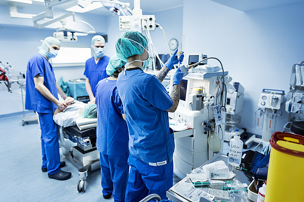 In einem Operationsaal: vier Personen in OP-Kleidung bereiten eine OP vor